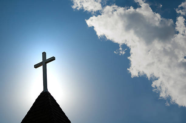 Church steeple cross against a bright sky